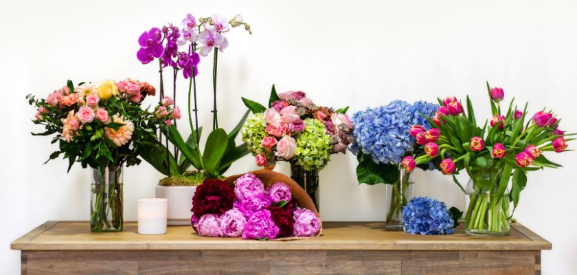 Colorful floral arrangements featuring roses, tulips, and orchids in elegant vases.