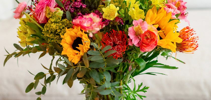 Vibrant mixed flower bouquet featuring sunflowers, roses, and greenery, perfect for celebrations.