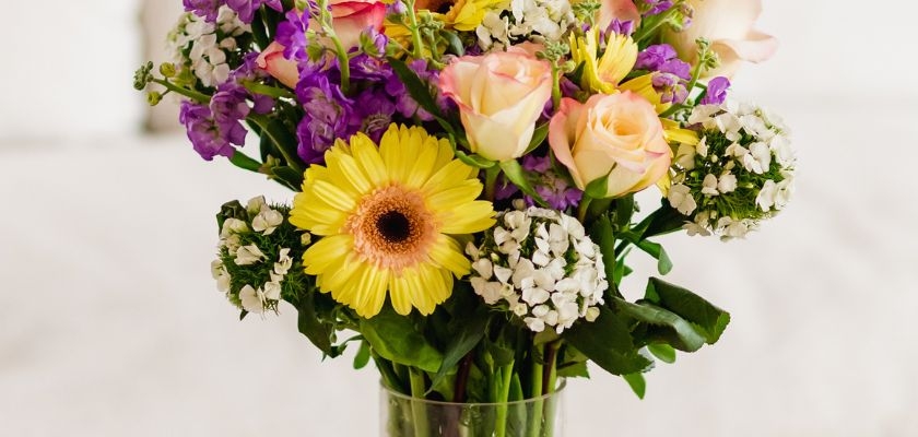 Bright and cheerful floral arrangement featuring gerbera daisies, roses, and colorful blooms.