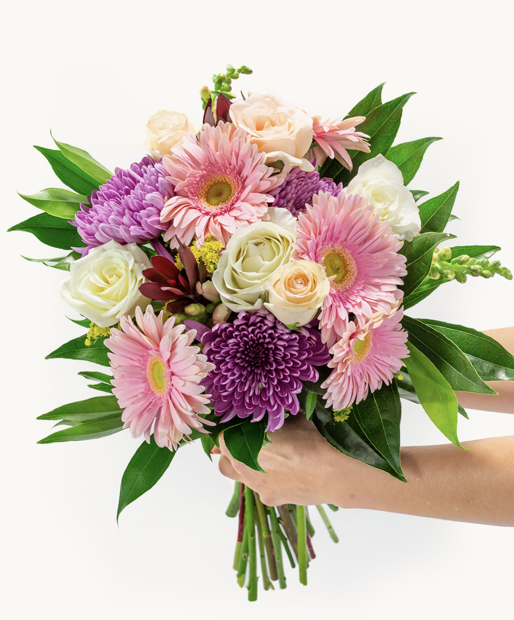 Vibrant spring bouquet featuring pink gerbera daisies, purple flowers, and lush greenery.