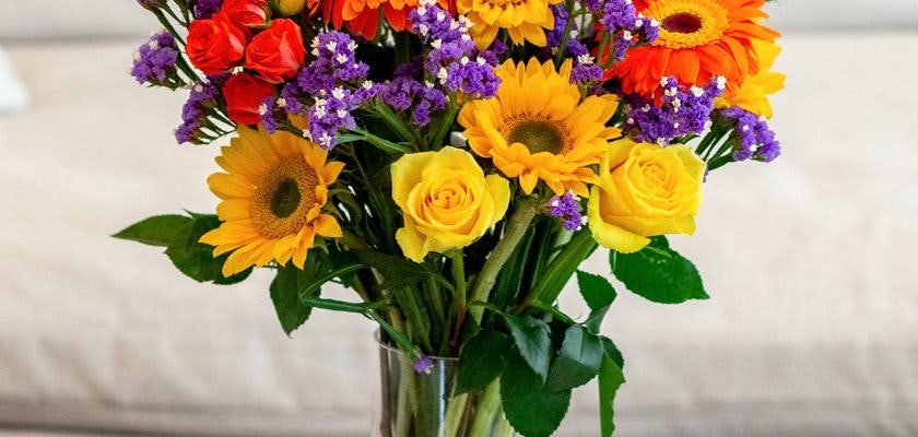 Vibrant floral arrangement featuring sunflowers, roses, and colorful blooms in a vase.