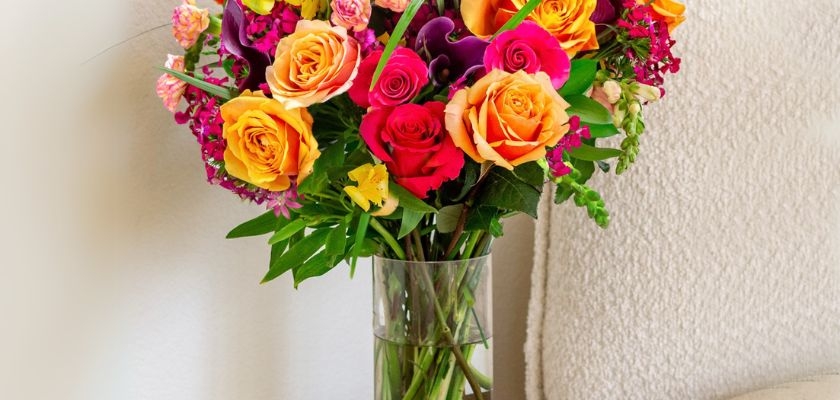Vibrant floral bouquet featuring orange and pink roses, complemented by colorful blooms.