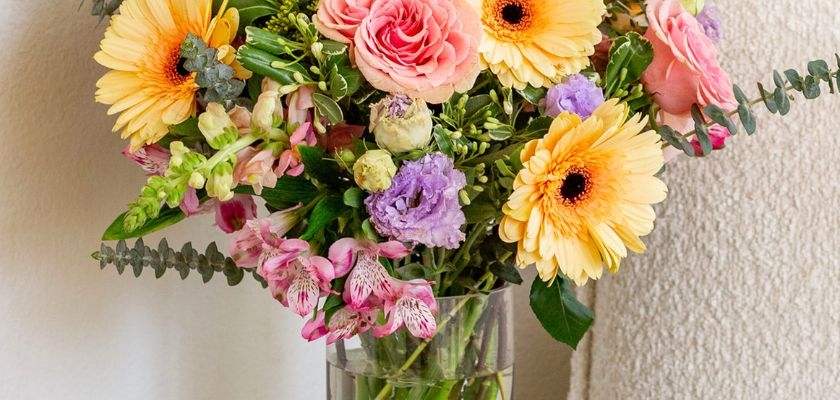 Vibrant floral arrangement featuring pink roses, yellow gerberas, and mixed blooms.