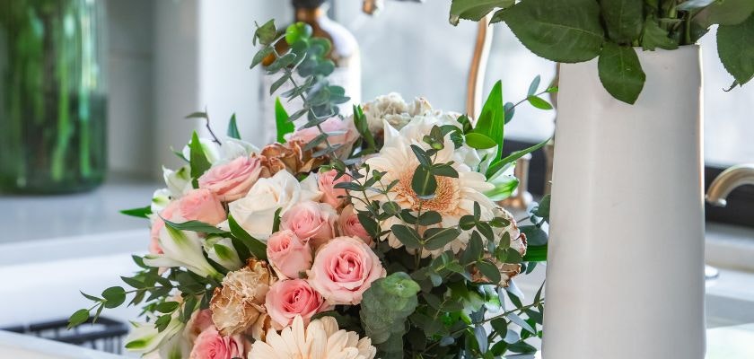 Elegant floral arrangement featuring soft pink roses, white blooms, and lush greenery in a vase.