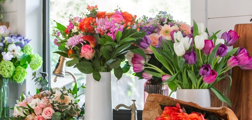 Colorful floral arrangements featuring roses, tulips, and daisies in elegant vases.