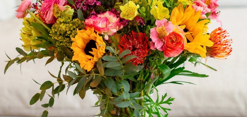 Vibrant floral arrangement featuring sunflowers, roses, and greenery in a charming bouquet.