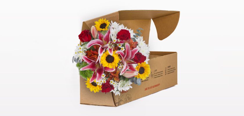 Vibrant floral arrangement featuring sunflowers, lilies, and roses in a gift box.