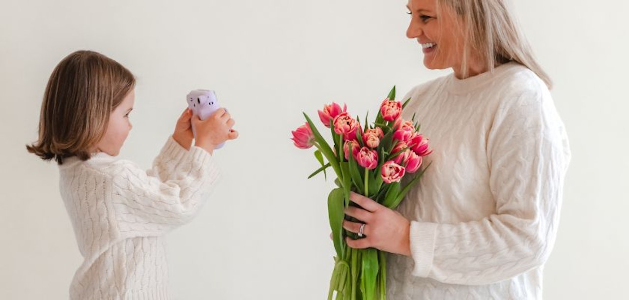 A joyful moment between a mother and daughter, celebrating with a vibrant tulip bouquet.