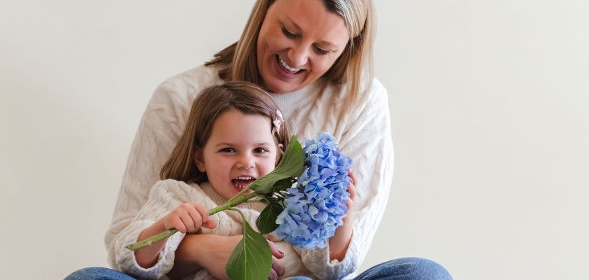 A joyful moment between mother and daughter with a blue hydrangea bouquet, celebrating love.
