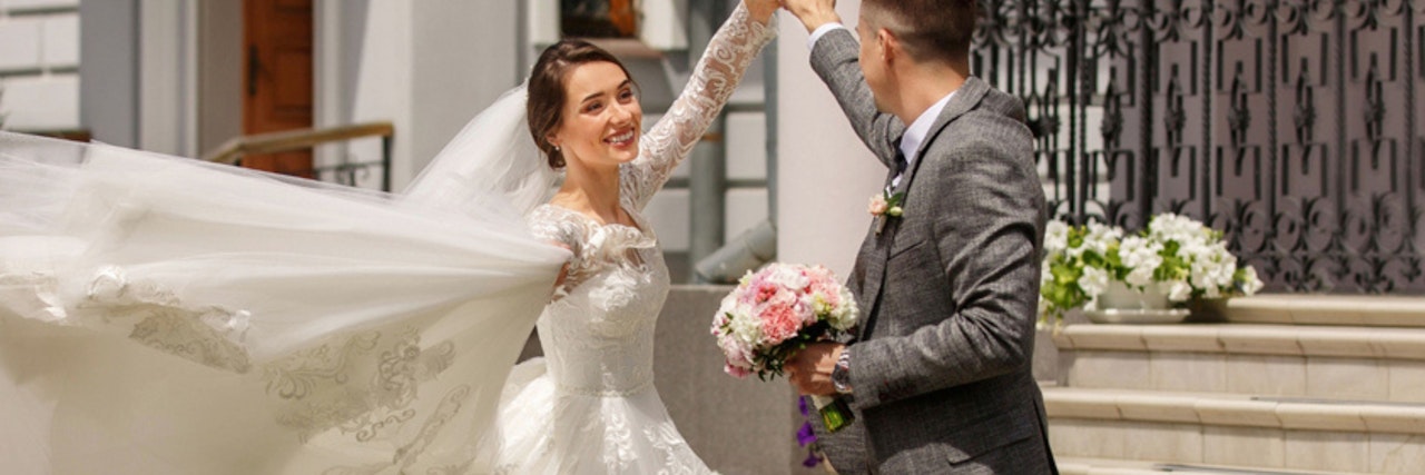 Joyful bride and groom dancing at their wedding, surrounded by floral decor.