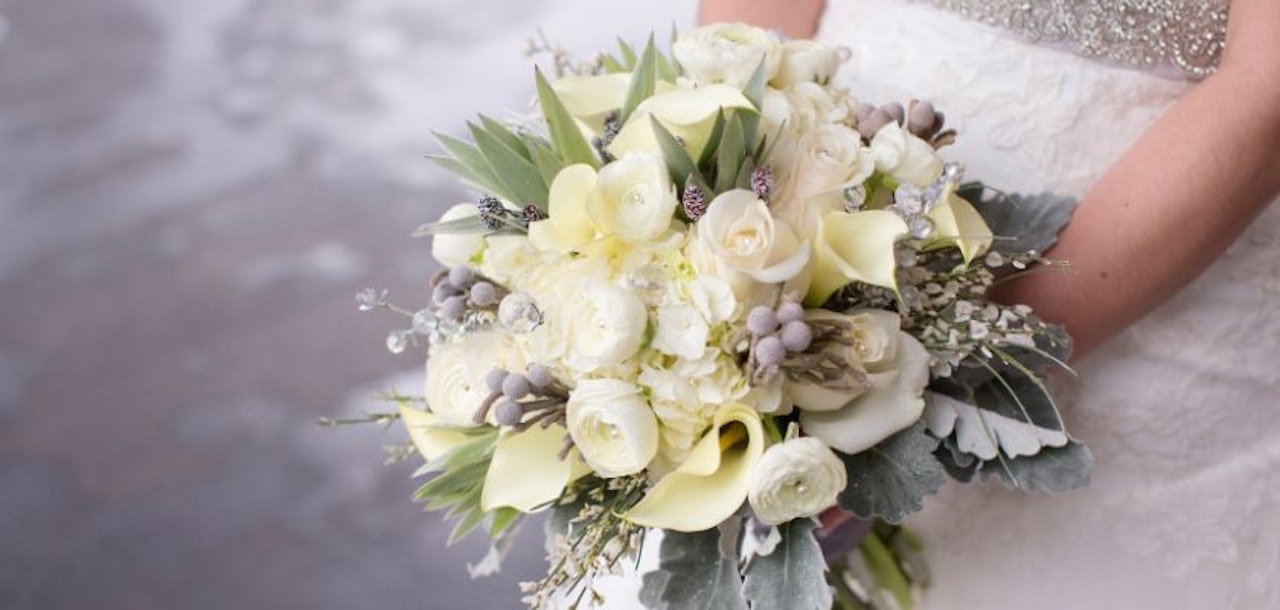 Elegant bouquet featuring white roses, greenery, and soft accents, ideal for weddings.