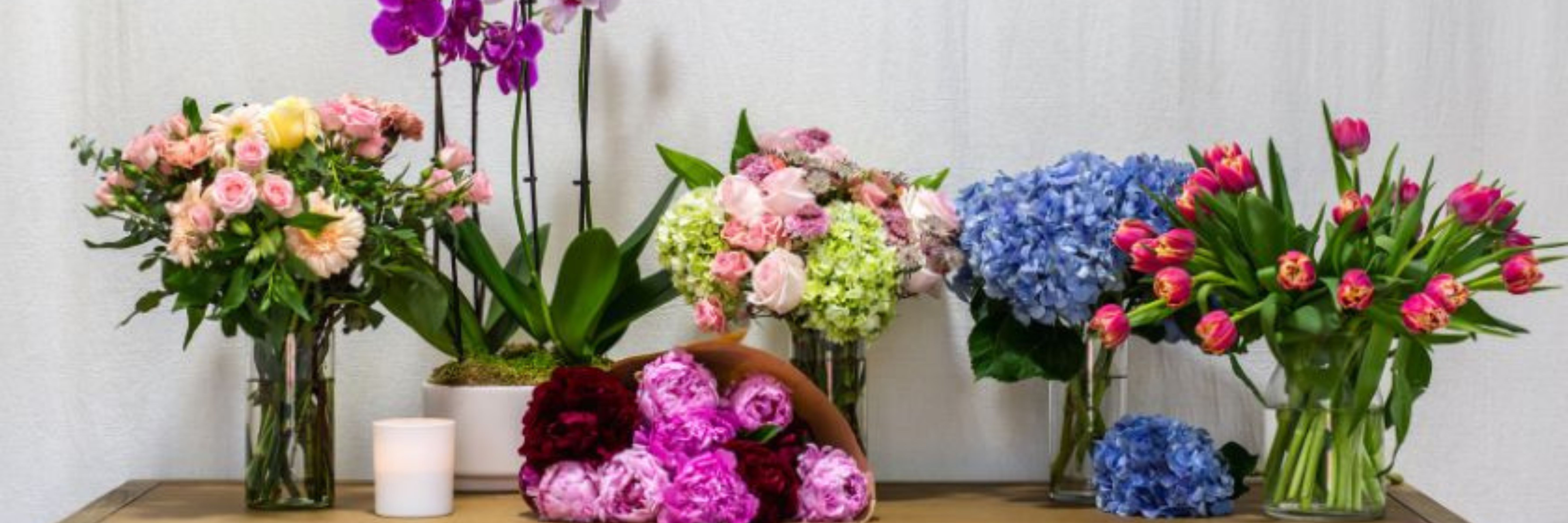Vibrant flower arrangement featuring roses, tulips, and orchids in elegant vases.