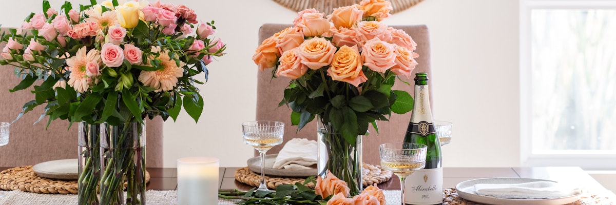 Elegant floral arrangement with pink and peach roses on a beautifully set dining table.