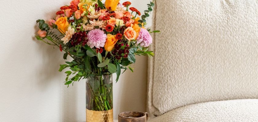 Vibrant floral arrangement featuring roses, daisies, and greenery in a stylish vase.