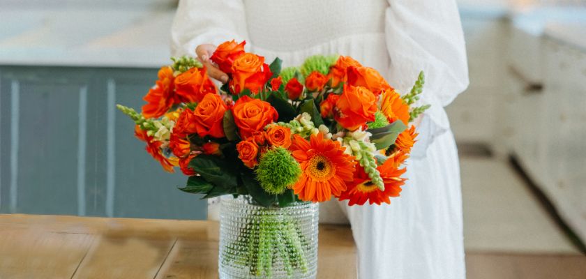 Vibrant orange floral bouquet with roses and gerberas in a glass vase, enhancing any space.