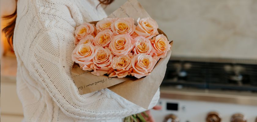 Delicate bouquet of peach roses wrapped in kraft paper, perfect for gifting.