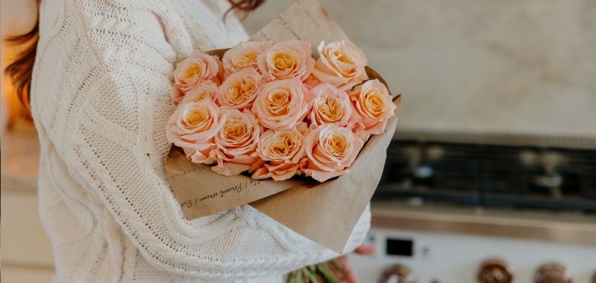 Delicate bouquet of peach roses wrapped in kraft paper, perfect for gifting.
