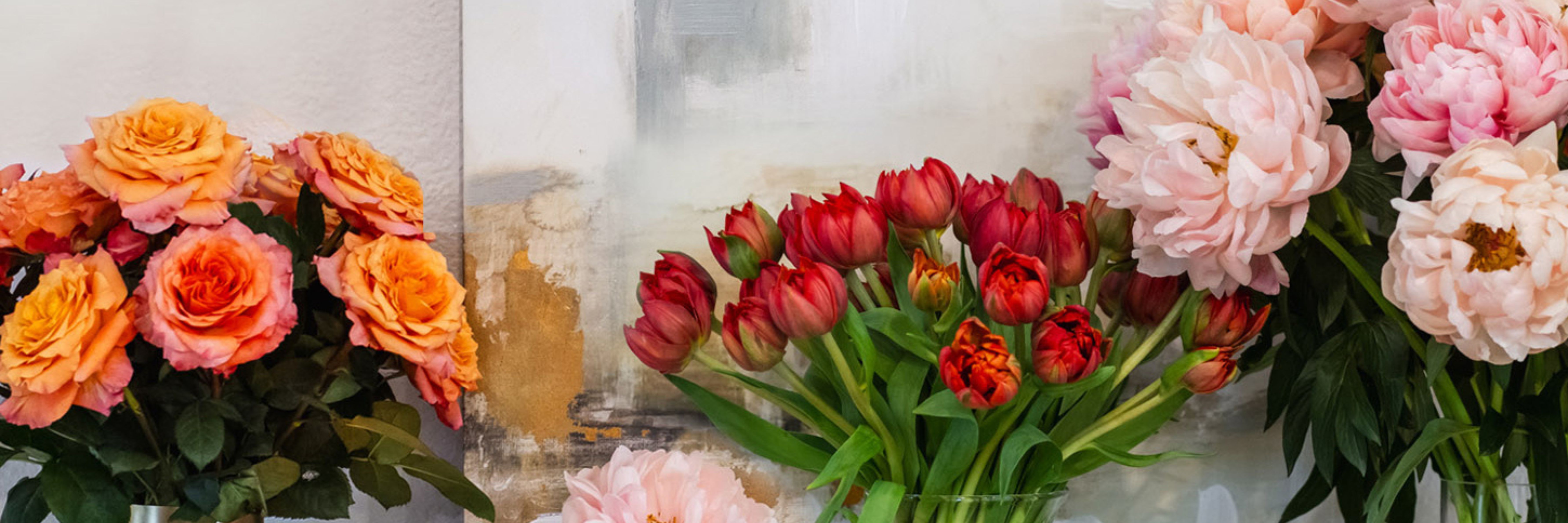 Vibrant floral arrangement featuring orange roses, red tulips, and pink peonies on display.