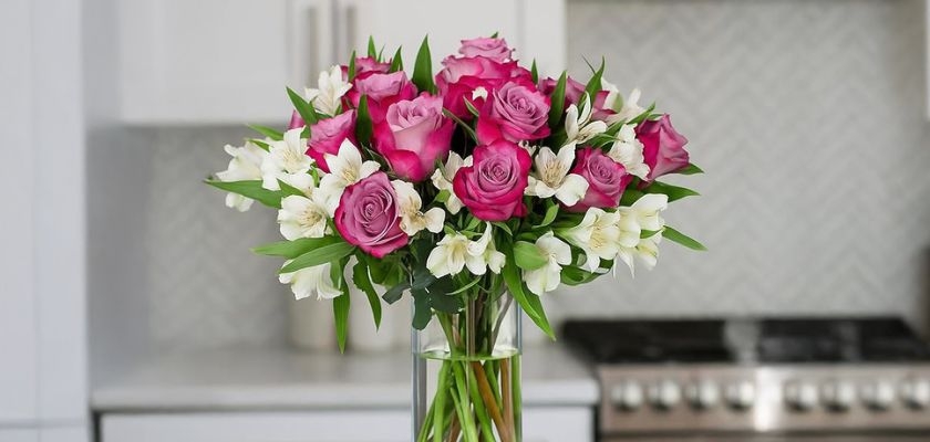 Vibrant bouquet of pink roses and white flowers in a sleek glass vase, brightening any kitchen.