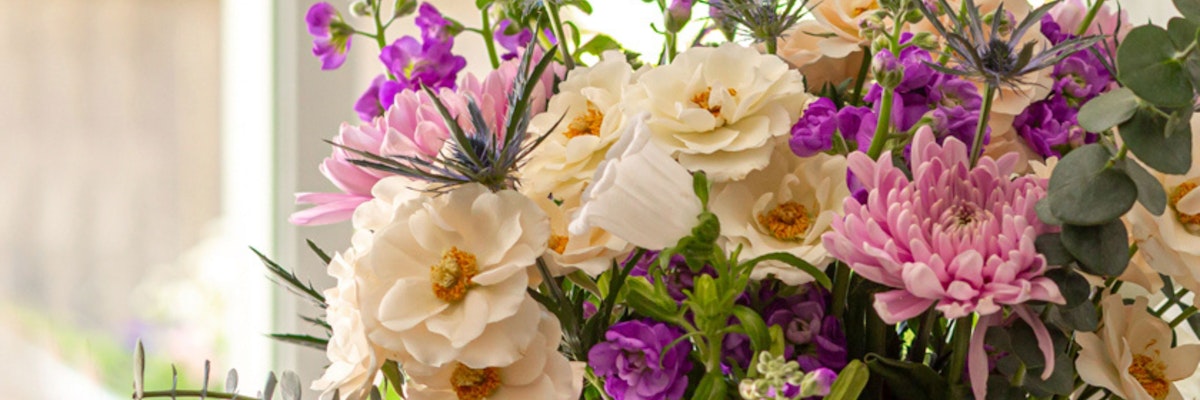 Elegant floral arrangement featuring soft pink, purple, and white blooms, exuding charm.