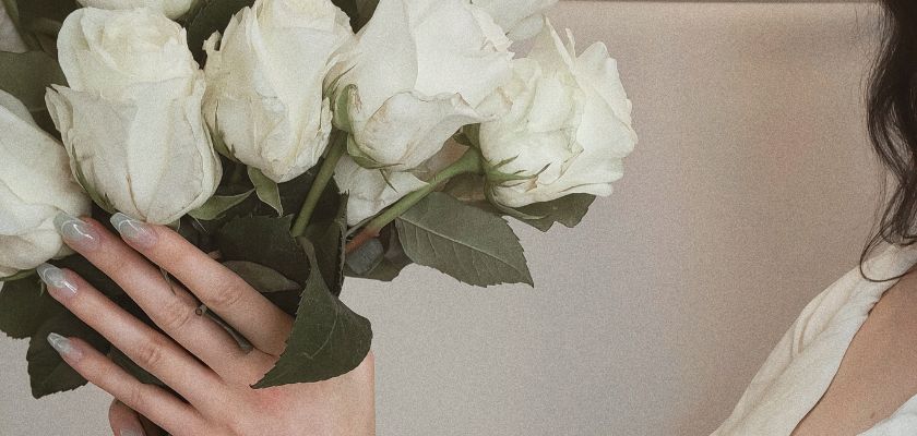 Elegant bouquet of white roses held by a person, showcasing delicate beauty.