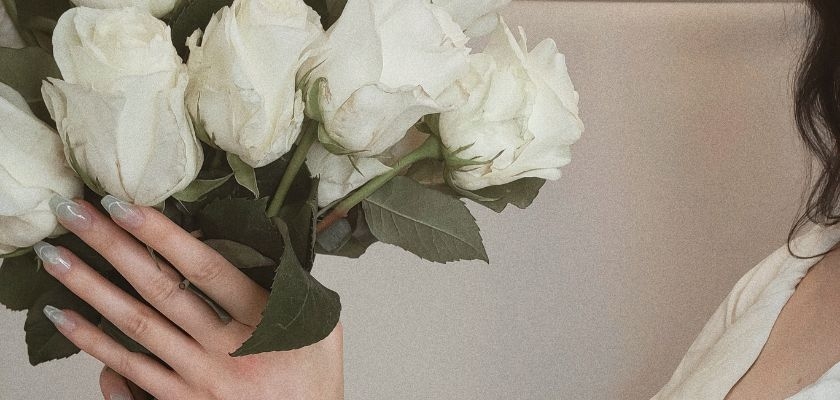 Elegant bouquet of white roses held by a person, showcasing delicate beauty.