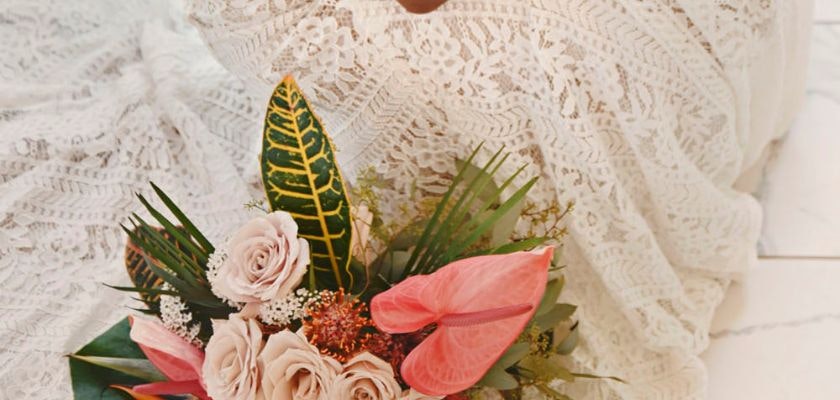 Elegant floral arrangement with blush roses, tropical leaves, and vibrant anthuriums.