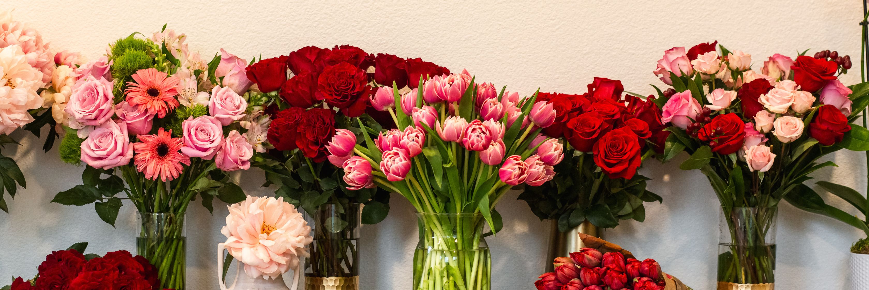 Colorful floral display featuring red roses, pink tulips, and cheerful gerbera daisies.