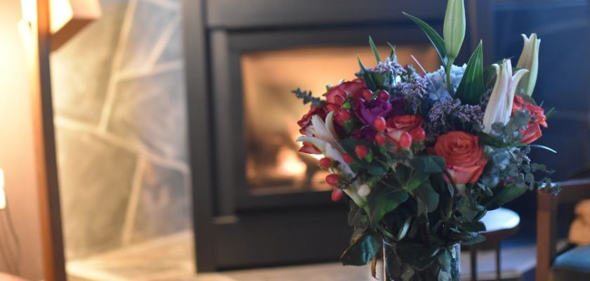Vibrant floral arrangement with roses and lilies against a cozy fireplace backdrop.