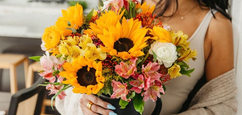 Bright floral arrangement featuring sunflowers, roses, and alstroemeria in a stylish bouquet.