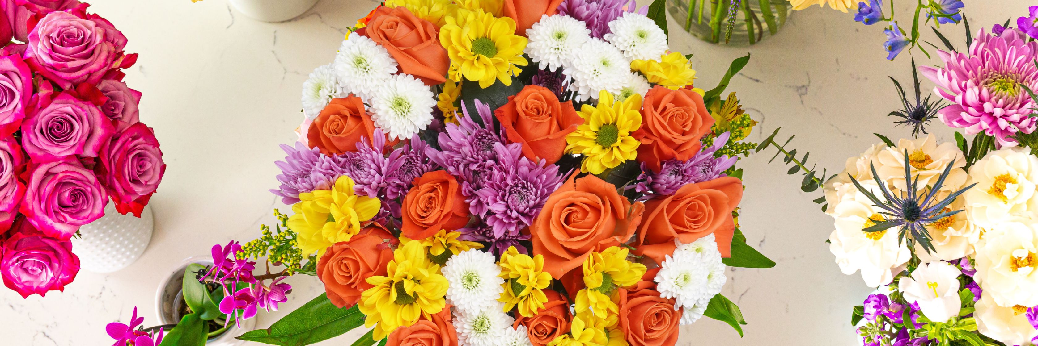 Vibrant floral bouquet featuring roses, daisies, and colorful blooms in a stylish arrangement.