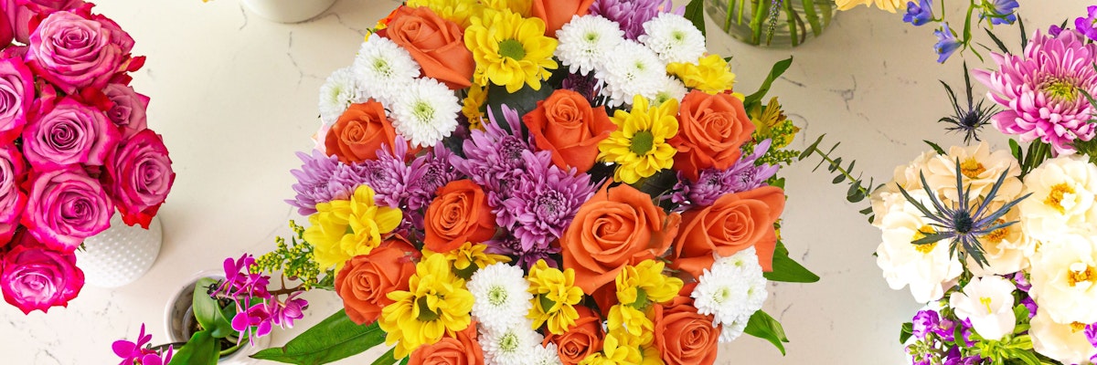 Vibrant floral bouquet featuring roses, daisies, and colorful blooms in a stylish arrangement.