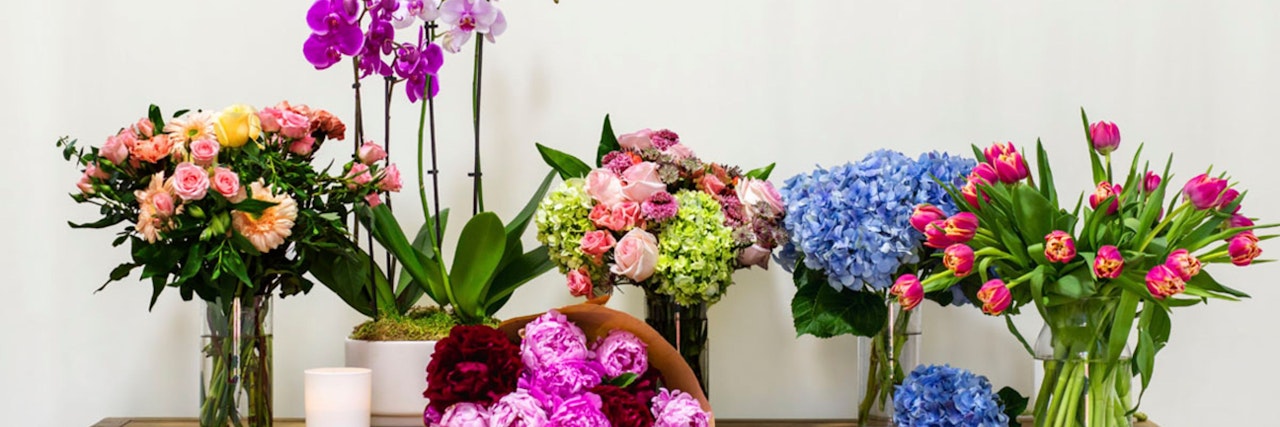 Colorful floral arrangements featuring roses, tulips, and orchids in stylish vases on a table.