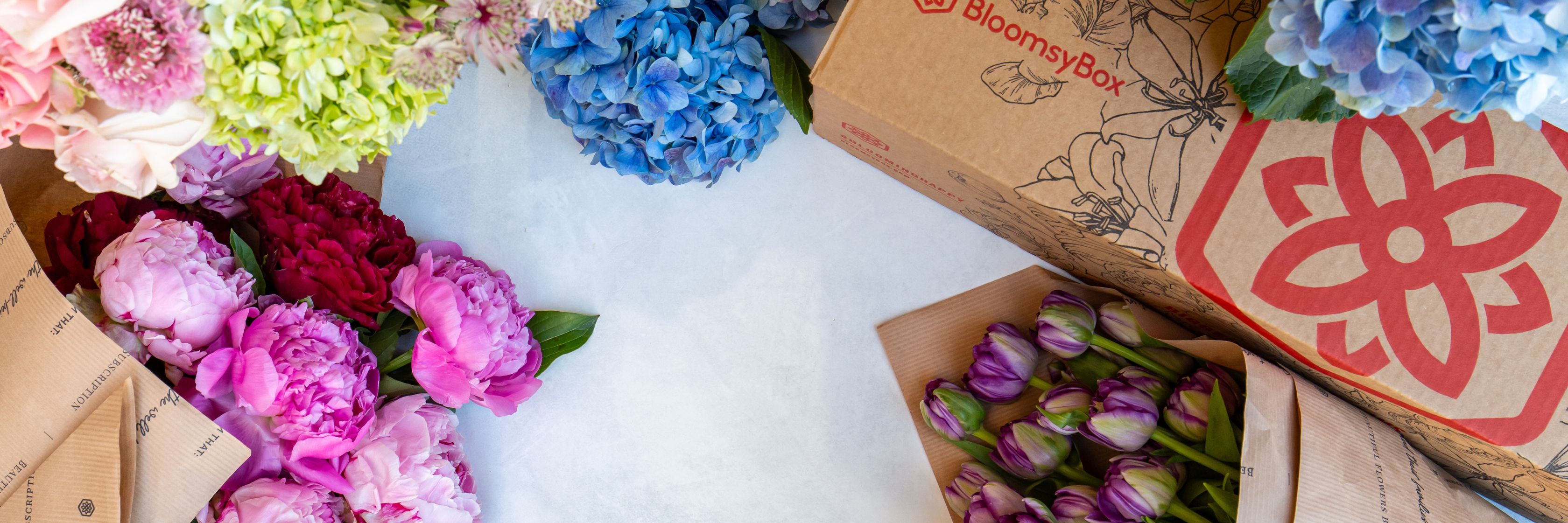 Colorful floral arrangement featuring peonies, tulips, and hydrangeas in stylish packaging.
