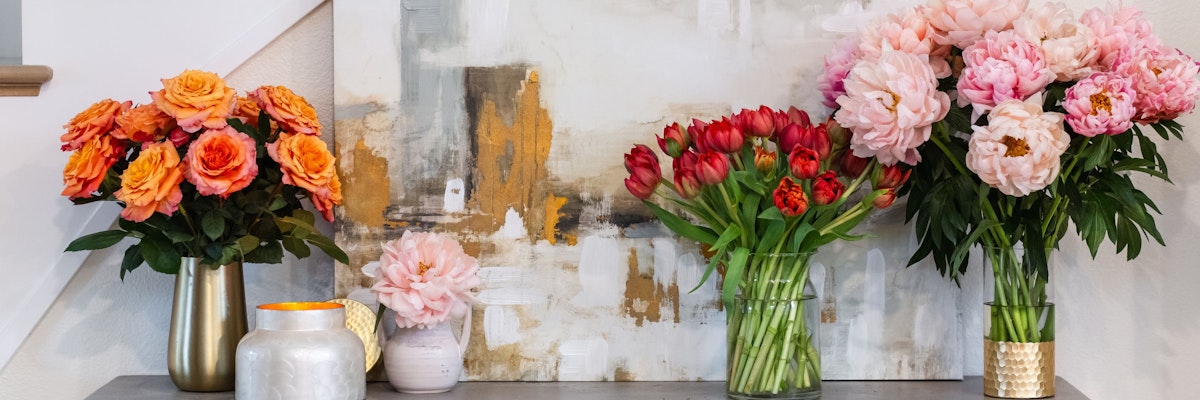 Three elegant floral arrangements featuring roses and peonies in stylish vases.