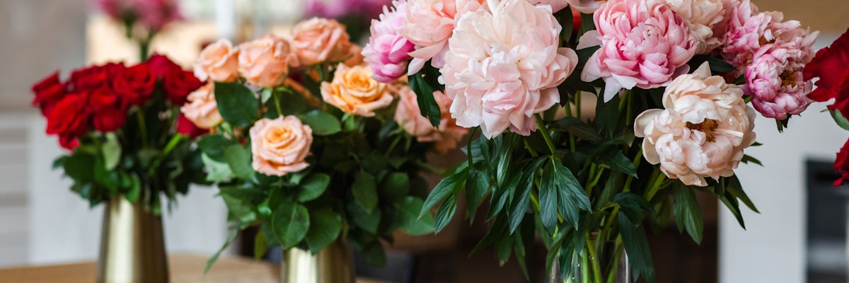 Vibrant floral arrangement featuring red roses and soft peonies in elegant vases.