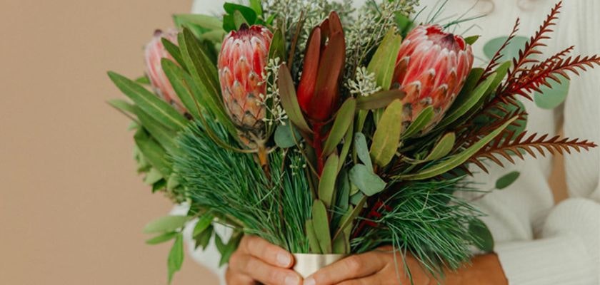 A vibrant bouquet featuring proteas, greenery, and assorted foliage, perfect for gifting.