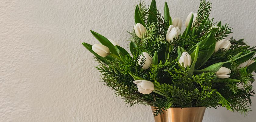 Elegant white tulips and lush greenery beautifully arranged in a sleek metal vase.