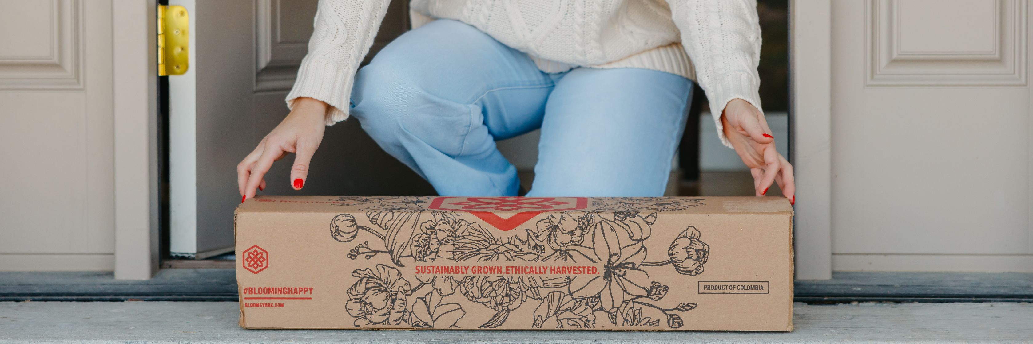 A person joyfully receiving a sustainable floral delivery at their doorstep.