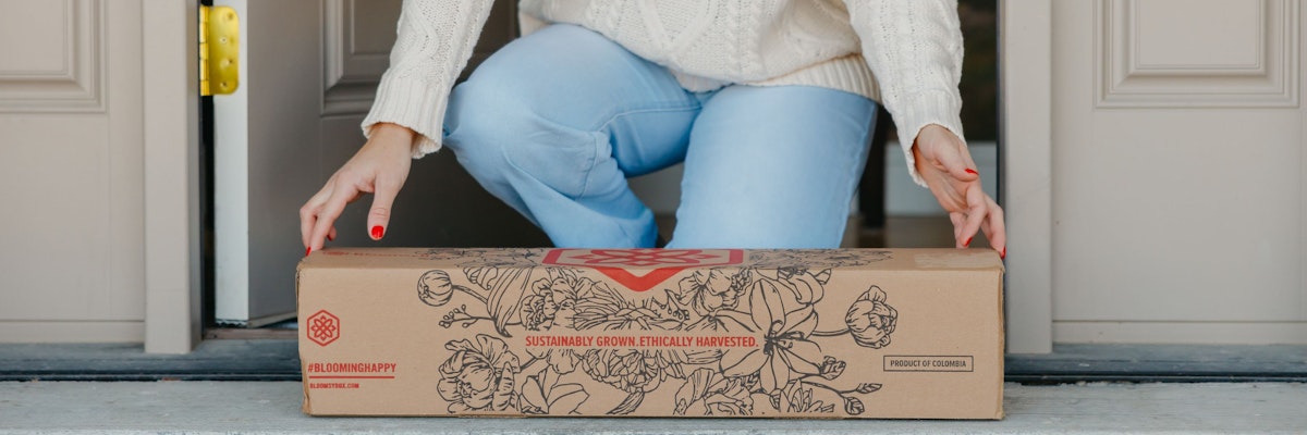 A person joyfully receiving a sustainable floral delivery at their doorstep.