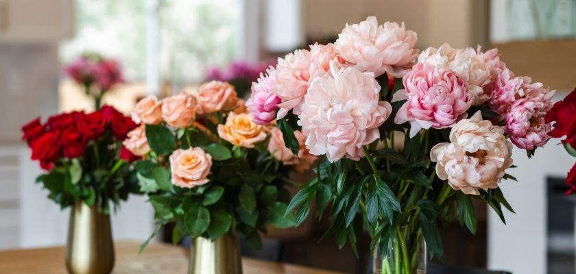 Beautiful arrangement of pink peonies and roses in elegant vases, ideal for any occasion.