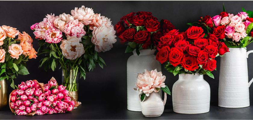 Vibrant floral display featuring red roses, peonies, and pink blooms in elegant vases.