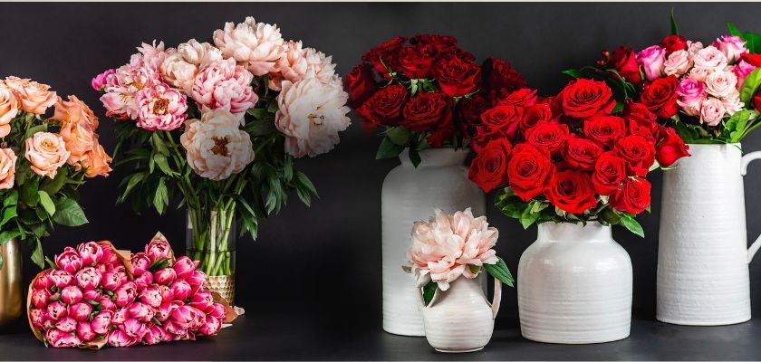 Vibrant floral display featuring red roses, peonies, and pink blooms in elegant vases.