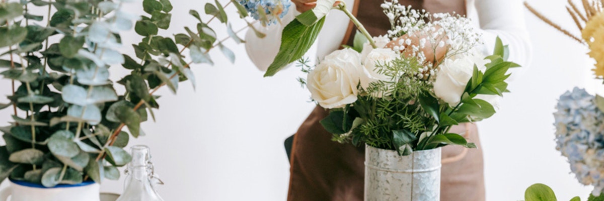 Floral designer arranging elegant white roses with greenery in a stylish bouquet.