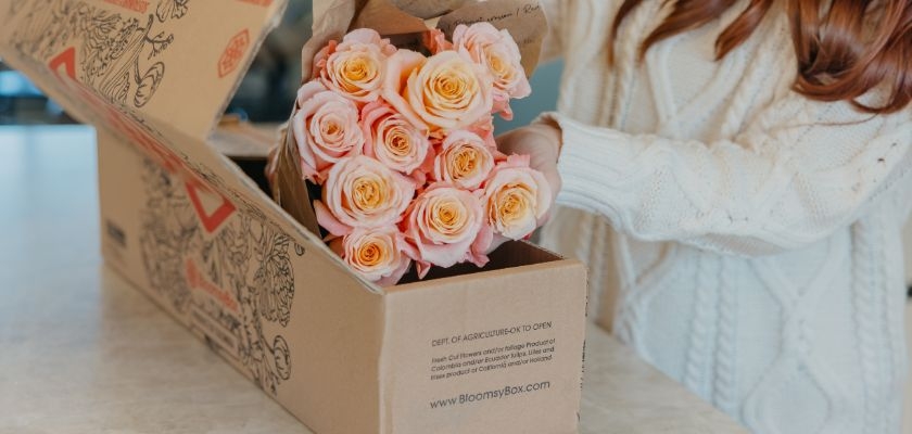 Elegant bouquet of peach roses being unpacked from a BloomsyBox delivery.