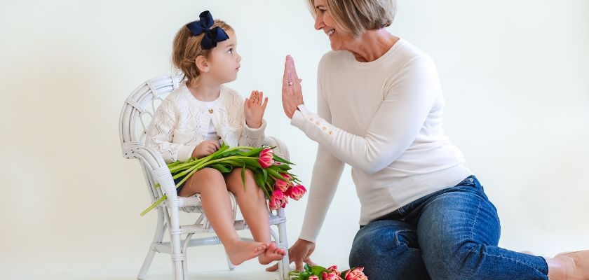 A joyful interaction between a child and grandmother with fresh pink tulips, showcasing love.