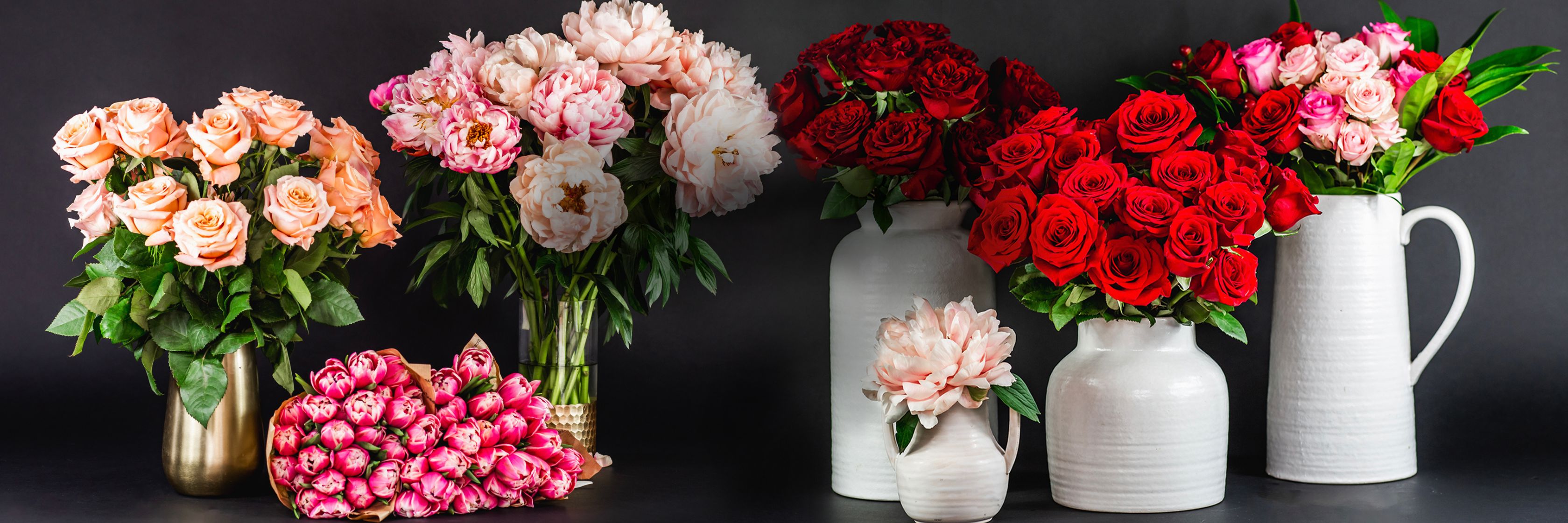 Vibrant display of red and pink roses in elegant vases and bouquets, perfect for celebrations.
