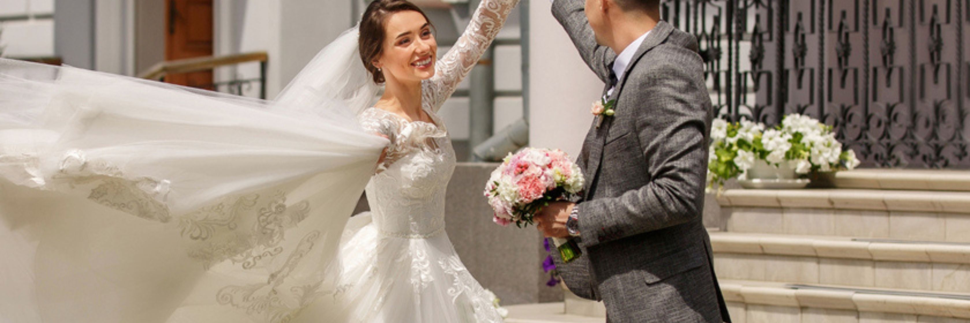Joyful bride and groom celebrating their wedding day with a floral bouquet and elegant attire.
