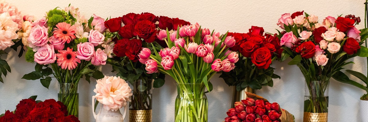 Vibrant flower display featuring red roses, tulips, and pink gerbera daisies in elegant vases.