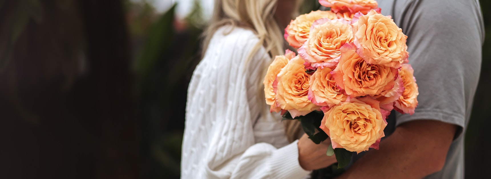 A romantic embrace featuring a vibrant bouquet of peach roses, perfect for special moments.